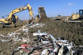 Operating Engineers Cover Demolition Debris from the Analytical Laboratory with Impacted Soil in Cell 4 of the On-Site Disposal Facility.
A balanced approach to waste disposition has been developed at Fernald, one in which the majority of the site's contaminated material will be placed in an On-Site Disposal Facility (OSDF) for its final disposition, where as, a smaller volume of more highly contaminated waste will be sent off site. The OSDF is being constructed on the east side of the Fernald Site and will ultimately hold approximately 2.5 million cubic yards of impacted material. The facility is being constructed in phases. Phase V consists of waste placement in Cells 3, 4, 5, and 6, construction of the Cell 7 and 8 liners, the placement of the final cover on all remaining cells and screening of clay liner and cover material in the Borrow Area.
Keywords: Fernald Closure Project Fernald Green Salt Plant, Feed Materials Production Center, Fernald, Ohio (FEMP)