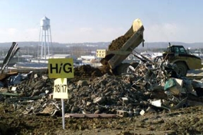 A Teamster Places Impacted Material Around Demolition Debris in Cell 4 of the On-Site Disposal Facility.
A balanced approach to waste disposition has been developed at Fernald, one in which the majority of the site's contaminated material will be placed in an On-Site Disposal Facility (OSDF) for its final disposition, where as, a smaller volume of more highly contaminated waste will be sent off site. The OSDF is being constructed on the east side of the Fernald Site and will ultimately hold approximately 2.5 million cubic yards of impacted material. The facility is being constructed in phases. Phase V consists of waste placement in Cells 3, 4, 5, and 6, construction of the Cell 7 and 8 liners, the placement of the final cover on all remaining cells and screening of clay liner and cover material in the Borrow Area 
Keywords: Fernald Closure Project Fernald Green Salt Plant, Feed Materials Production Center, Fernald, Ohio (FEMP)