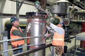 Workers Install Insulation on Piping in the TTA Building.
8,900 cubic yards of high activity low-level waste material will be removed from Silos 1 and 2, processed and shipped off site for disposal. This material was generated from 1951 and 1960 as a waste by-product from the processing of high-grade uranium ores. The Silos 1 and 2 material, also known as K-65 materials, contains radium and thorium radionuclides. Waste Retrieval Project will consist of six major systems; Silos Waste Retrieval System; Decant Sump Waste Retrieval System; Transfer Tank Area; Transfer Tank Waste Retrieval System; Radon Control System; and the Full Scale Mock-up System. Once the waste is removed from the silos it will then be stabilized with a formulation of flyash and Portland cement before being containerized for shipment. 
Keywords: Fernald Closure Project Fernald Green Salt Plant, Feed Materials Production Center, Fernald, Ohio (FEMP)