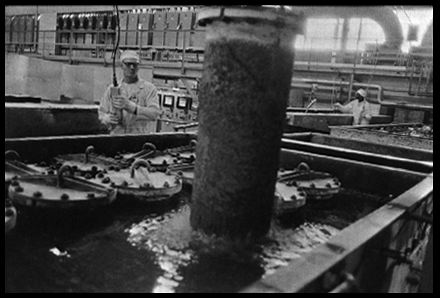 Cooling the Derby
The hot cylinder containing new uranium derby metal is lowered into water for cooling. 

Feed Materials production Center, Fernald, Ohio. December 17, 1985.
Keywords: Fernald Green Salt Plant, Feed Materials Production Center, Fernald, Ohio (FEMP)