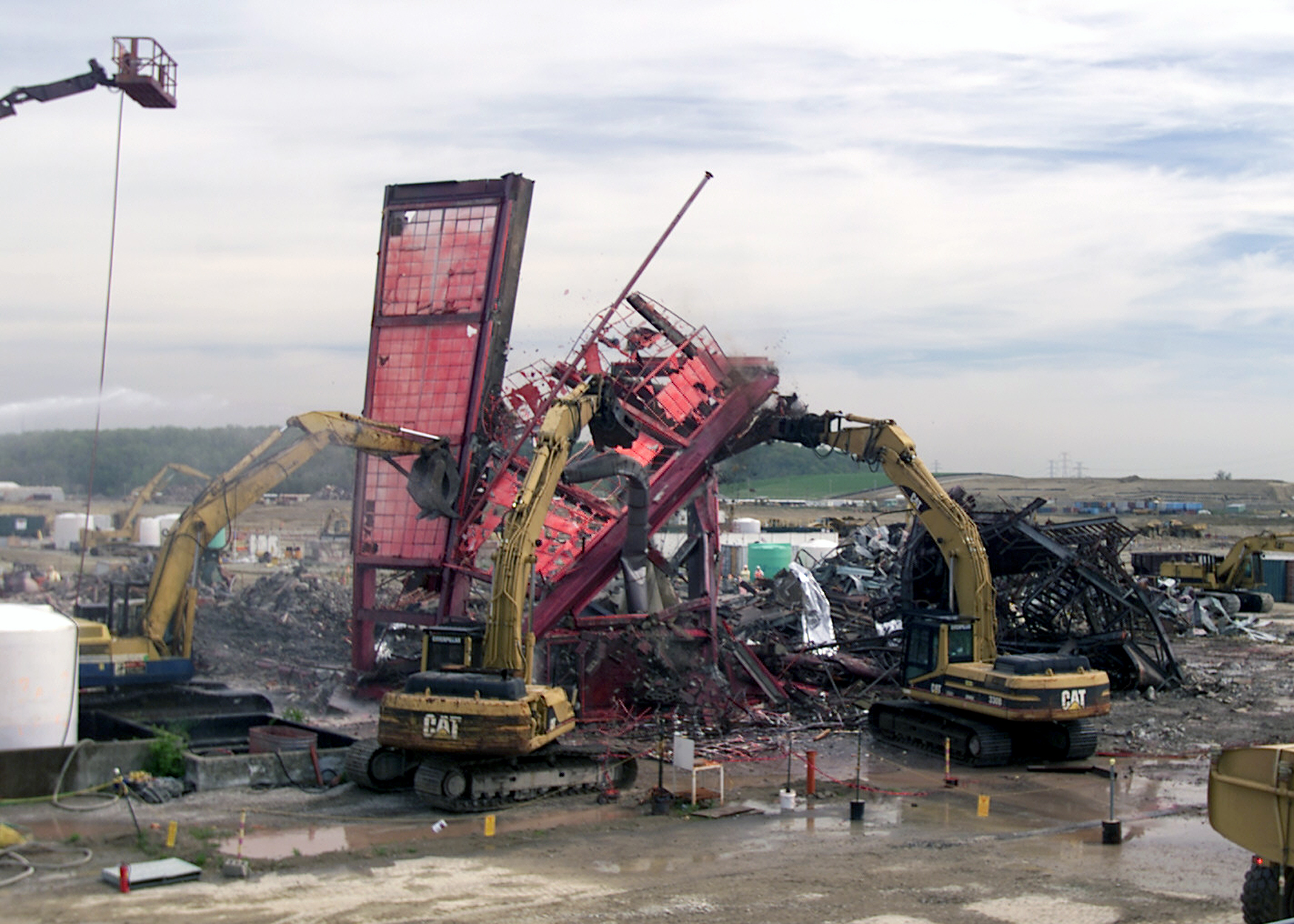 Operating Engineers Raze the Last Section of the Pilot Plant. The Facility was the Last of 10 Plants to be Removed from the Fernald Skyline.
The Pilot Plant was the first plant to go on line at Fernald. The plant served as an operating prototype for all phases of the uranium metal production process and a training area for new operators. Later, the plant's main function became the conversion of uranium hexaflouride (UF6) to uranium tetraflouride (UF4), called green salt, for use in the metal production process. Workers also purified thorium and converted thorium nitrate to thoria gel oxides in the plant. The D&D of the plants consists of surface decontamination, building and equipment dismantlement, size reduction of building material and the loading of demolition debris into rolloff boxes for transfer to the On-Site Disposal Facility. 
Keywords: Fernald Closure Project Fernald Green Salt Plant, Feed Materials Production Center, Fernald, Ohio (FEMP)