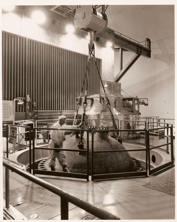 Showing the Head
Publicity photo from Consumers Power; accompanying caption reads: "Showing the 28-ton 'head,' or top, of Consumers Power Company's Nuclear Plant reactor itself.  The reactor in Michigan's first operating nuclear power plant rests below this head, which the plant operators remove at scheduled times for certain tests and maintenance work.  
"The plant is being used in a research and development program, and any of its 50,000 kilowatts of power not needed in the program is sent to Consumers Power Company's 900,000 electric customers in 61 counties throughout Michigan's Lower Peninsula."
Keywords: big rock point head reactor