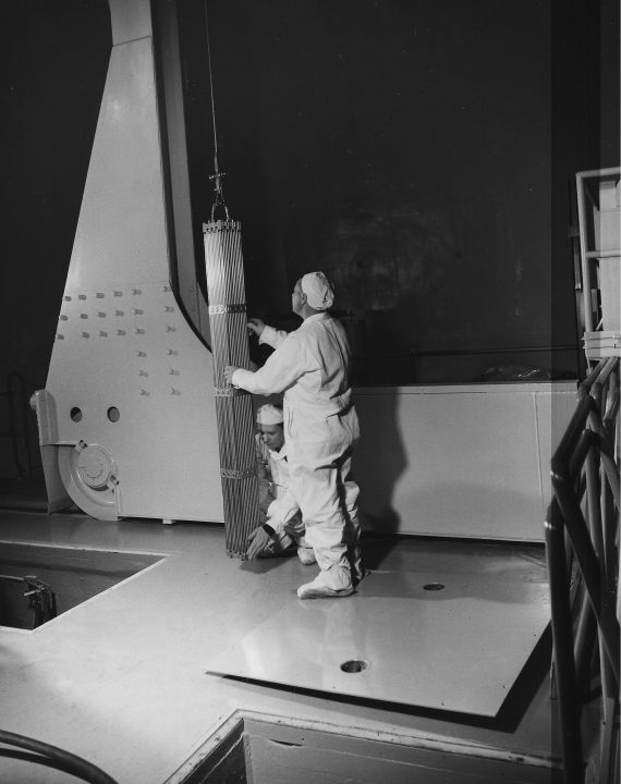 Examining a Fuel Bundle
Publicity photo from Consumers Power; accompanying caption reads "Men in white carefully examine a bundle of fuel at Consumers Power Company's Big Rock Point Nuclear Plant, near Charlevoix.  The fuel bundle has already successfully passed rigid inspection, but even so, operators take a last-minute look before placing the fuel in the reactor core.  The bundle contains 144 rods filled with enriched uranium pellets.  The plant helps supply electric power to the Consumers electric system, which serves 61 of the 68 counties in Michigan's Lower Peninsula."
Keywords: big rock point fuel bundle rod examination